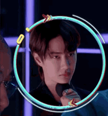 a man is holding a microphone in a neon circle and looking at the camera .