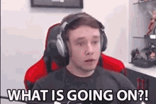 a man wearing headphones and a black shirt is sitting in a red chair .