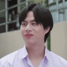 a young man in a white shirt is making a funny face while standing in front of a building .