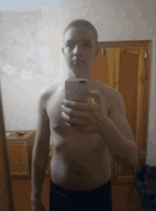 a shirtless man is taking a picture of himself in a mirror