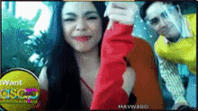 a man and a woman are posing for a picture in front of a sign that says ' mayward '