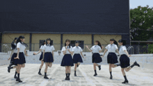 a group of girls are dancing in front of a large building