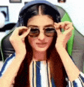 a woman wearing headphones and sunglasses is sitting in a green chair .