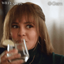a woman drinking from a glass with wildcards written on the bottom left