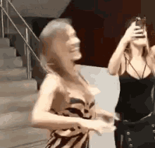 a woman is taking a picture of another woman with her phone .