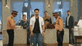 a group of people are standing around a man in a white shirt with the letter b on it