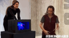 a man and a woman are standing in front of a box that says #skinwars on it
