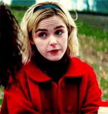 a woman is wearing a red coat and a black turtleneck