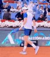 a man is holding a tennis racquet on a court with a sign that says " fundacion " on it