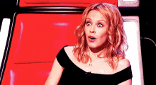 a woman with a surprised look on her face is sitting on a red chair .