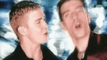 two men are standing next to each other and one of them is singing