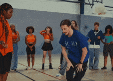 a man wearing a blue shirt that says scad is dancing in front of a group of people