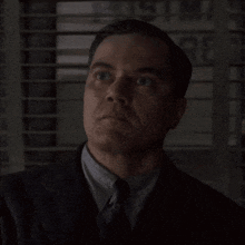 a man in a suit and tie looks up at the sky