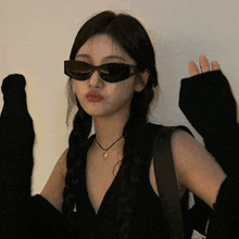 a woman wearing sunglasses and a black sweater is making a face .