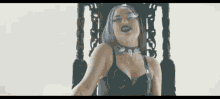 a woman in a black bra and choker is sitting on a throne .
