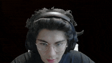 a man wearing headphones and glasses looks surprised with his mouth open