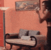 a woman is standing next to a couch in a living room holding a bottle of water .