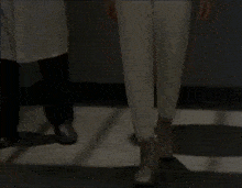 a person in white pants is walking next to another person in black pants
