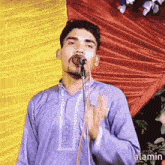 a man in a purple shirt is singing into a microphone with the word alamin below him