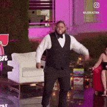 a man in a tuxedo is dancing in front of a woman sitting in a chair