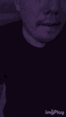a man with a beard is taking a selfie in the dark with his mouth open .