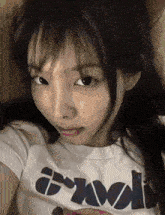 a close up of a woman taking a selfie wearing a white t-shirt with the word wool on it .