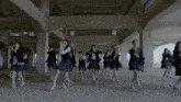 a group of girls in school uniforms are dancing in a dark hallway