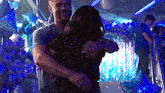 a man and woman are hugging each other in a room filled with blue balloons .