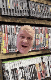 a man 's head is sticking out of a bookshelf filled with video games including xbox 360