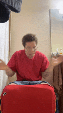 a man in a red shirt is sitting on a red towel in front of a mirror