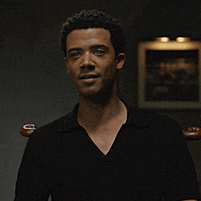 a man in a black shirt is sitting in a chair and looking at the camera