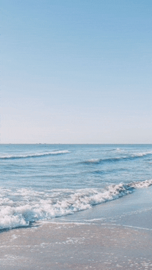 a beach with waves crashing on the shore on a clear day