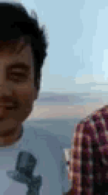 a man in a plaid shirt is taking a selfie with another man .