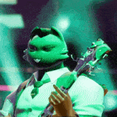 a green cat is holding a guitar in his hand