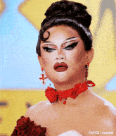 a drag queen is wearing a red choker and red earrings