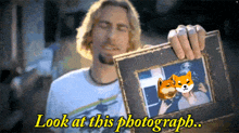 a man is holding a picture frame with the words look at this photograph below it