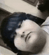 a close up of a person laying down with their eyes closed and a cat in the background .