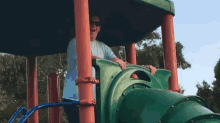 a man wearing sunglasses is sitting on a slide at a playground
