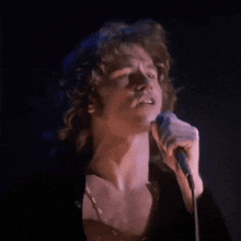 a man singing into a microphone with a dark background