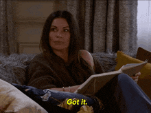 a woman sits on a couch reading a book with the words got it below her