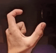 a close up of a person 's hand holding something with their thumb and index finger .