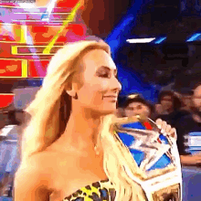 a woman in a leopard print top is holding a championship belt .