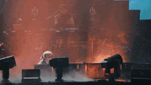 a man playing a piano on a stage with smoke coming out of the keyboard