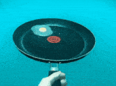 a person is holding a frying pan with two eggs and a tomato in it