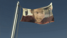 a flag with a picture of a boy on it is waving in the wind