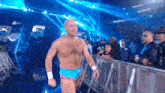 a shirtless wrestler is walking through a crowd in front of a sign that says smack down