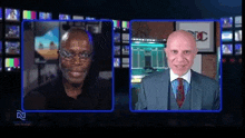 two men are talking to each other in front of a television screen .