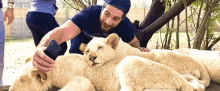 a man is petting a lion cub while taking a selfie