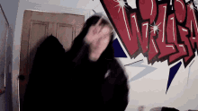a person is standing in front of a wall with graffiti on it that says ' crisis '