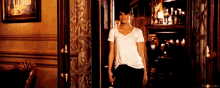 a woman in a white t-shirt is standing in a dark room with the word merrik on the bottom right
